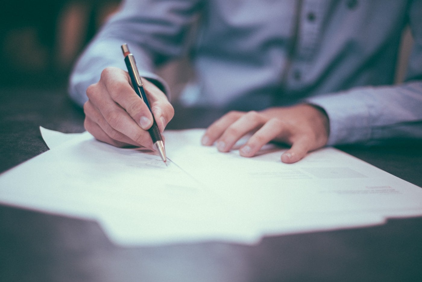 Hands organising documents at a desk, with no face visible